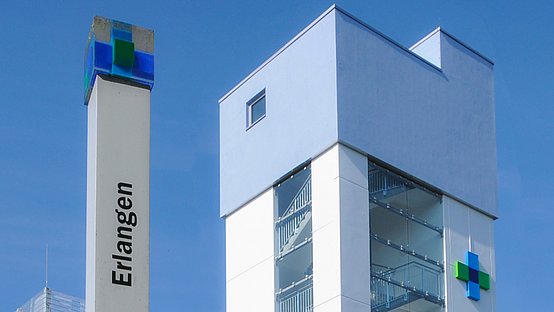 Turm des Klinikums mit dunkelblauem, hellblauem und grünem Logokreuz..