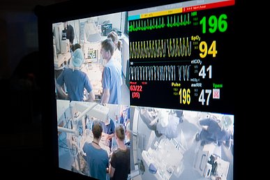 Blick auf einen Kontrollmonitor, auf dem vier Videobilder intensivmedizinischen Notversorgung während einer Simulationsübung zu sehen sind.