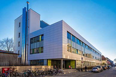 Straßenansicht des modernen Anbaus der Kinder- und Jugendklink mit glänzenden Fassadenplatten in Weiß verkleidet und prägender Glasfassade über die gesamte Breite des Gebäudes.