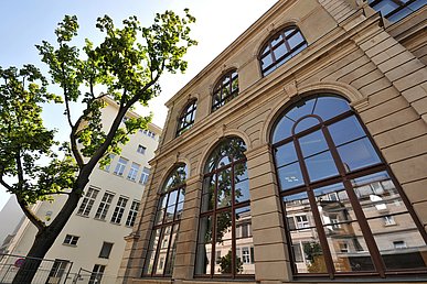 Blick von schräg unten auf die historischen Fassaden des Pathologischen Instituts und der Frauenklinik. In den hohen bogenförmigen Fenstern spiegelt sich des Fassade des Alten Universitätskrankenhauses.