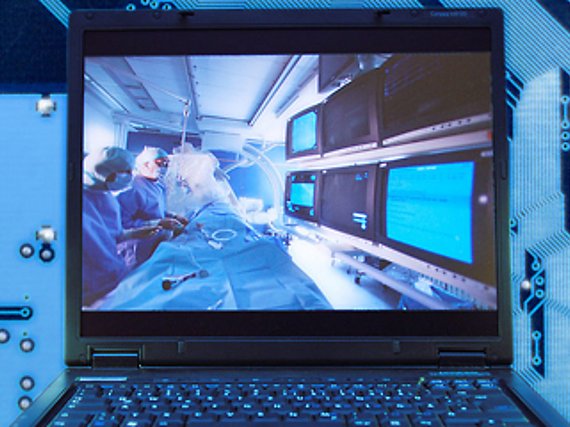 Foromontage: In der Mitte einer Comuter-Platine ist ein Laptop zu sehen, dessen Bildschirm das Bild einer kardiologischen Untersuchung mittels eines bildgebenden Verfahrens zeigt.