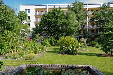 Hinter der Grünanlage des Arzneipflanzengartens liegt sie sonnenbeschienene Südseite der Kinder- und Jugendklinik mit Balkonen.