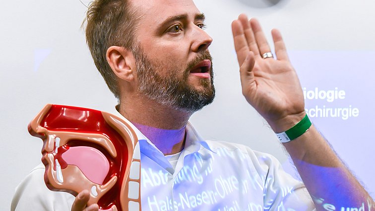 Vortragender bei Langer Nacht der Wissenschaften mit Querschnittsmodell eines Kopfes in der Hand.