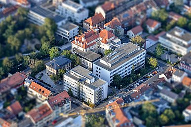 Luftaufnahme von Südost nach Nordwest. Diagonal im Bild scharf abgebildet das mehrstöckige Gebäudeensemble der modernen HNO-Klinik und der im historischen teil gelegene Bereich der Phoniatrie. Die umliegenden Gebäude sind unscharf.